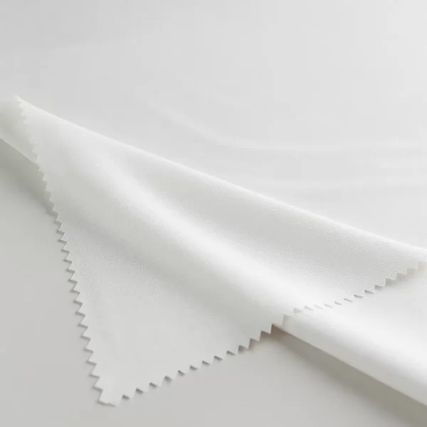 Muestra de tela Neopreno blanca doblada sobre fondo neutro con iluminación suave de estudio